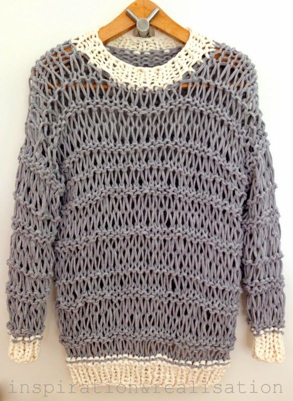 a gray knitted sweater hanging on a white wall