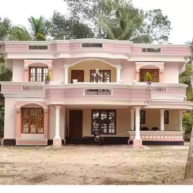 a pink and white house sitting on top of a dirt field