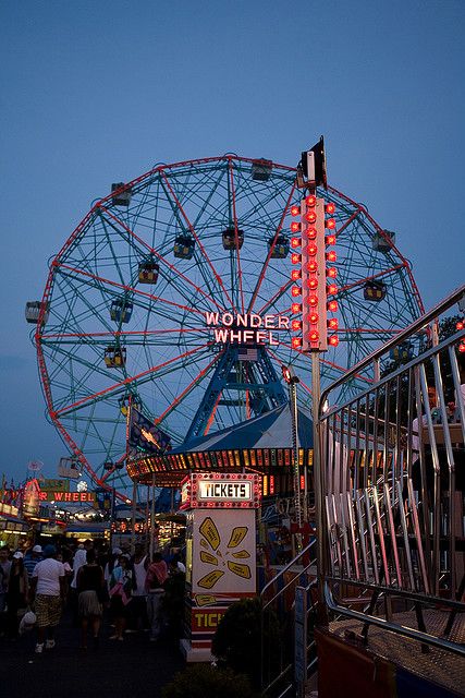 a ferris wheel at an amusement park with people walking around the area and onlookers