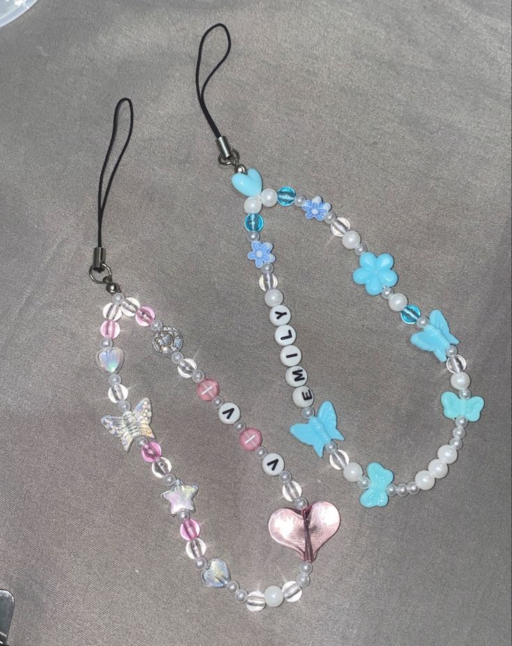 a close up of a necklace with beads and charms on a table next to a cell phone