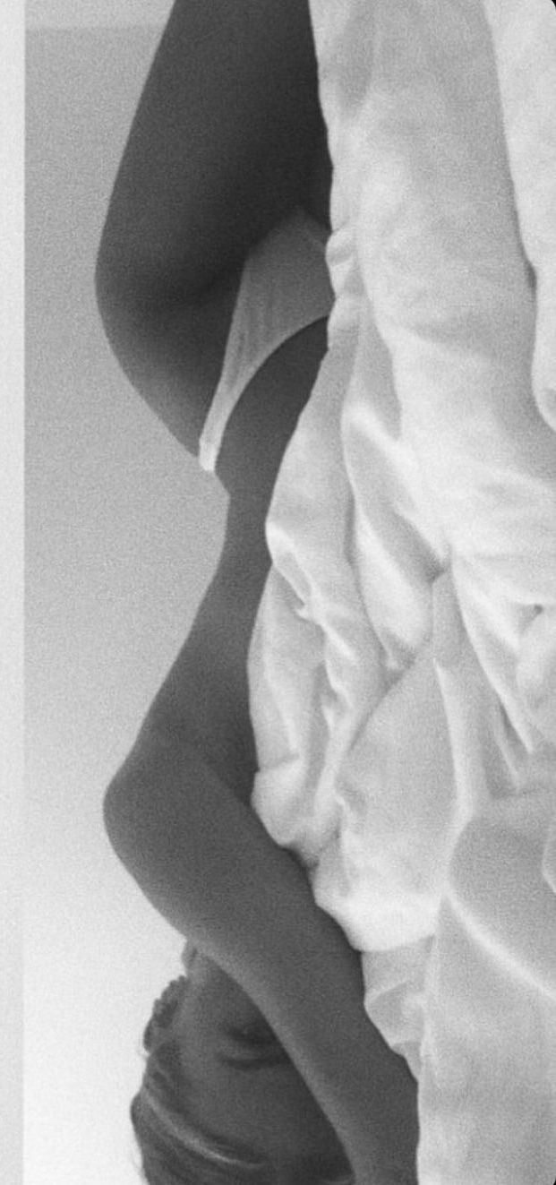 black and white photograph of a woman in bed with her back turned to the camera