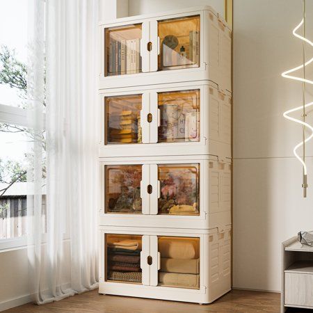 a tall white bookcase with glass doors on the front and sides, sitting in a room next to a window