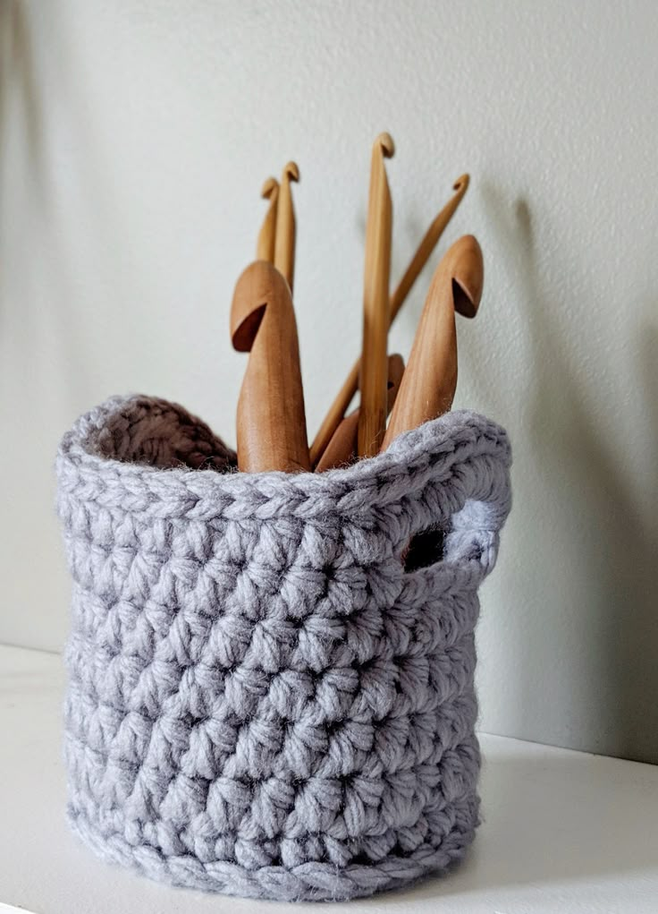 a crocheted basket with wooden spoons in it