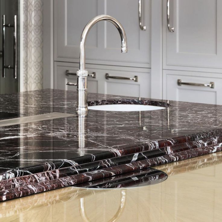 a kitchen with marble counter tops and stainless steel faucet, in the middle of an island