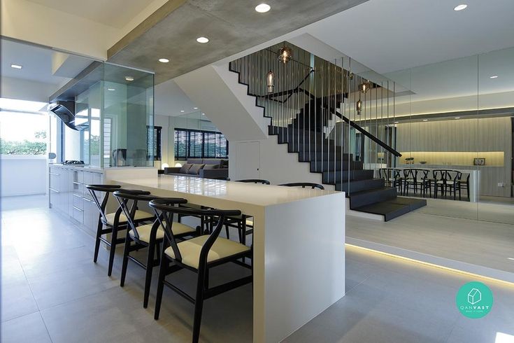 a dining room table with chairs under a stair case in front of a glass wall