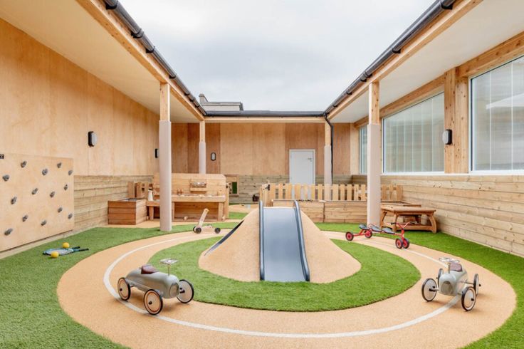 an indoor play area with artificial grass and wooden toys on the ground in front of it