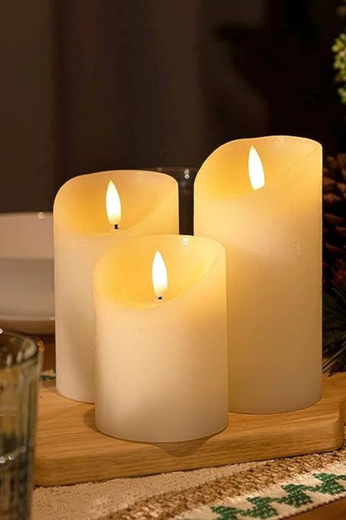 three lit candles sitting on top of a wooden tray