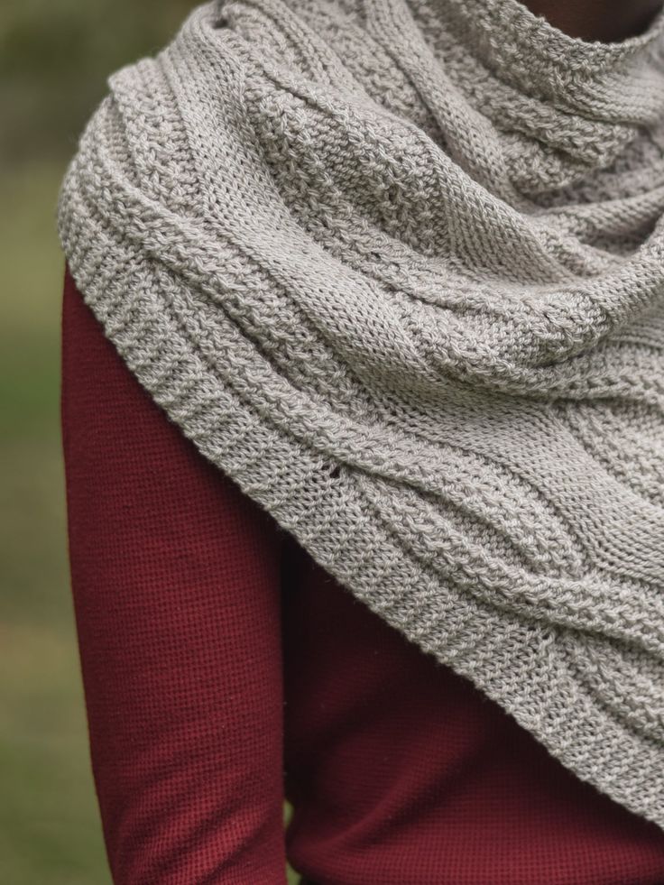 a woman wearing a white knitted shawl with red sleeves and a brown sweater