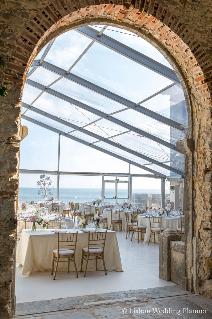 an outdoor dining area with tables and chairs set up for a wedding reception at the ocean