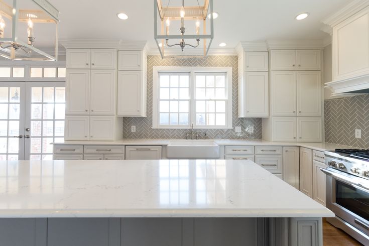 a large kitchen with white cabinets and an island in front of a stove top oven