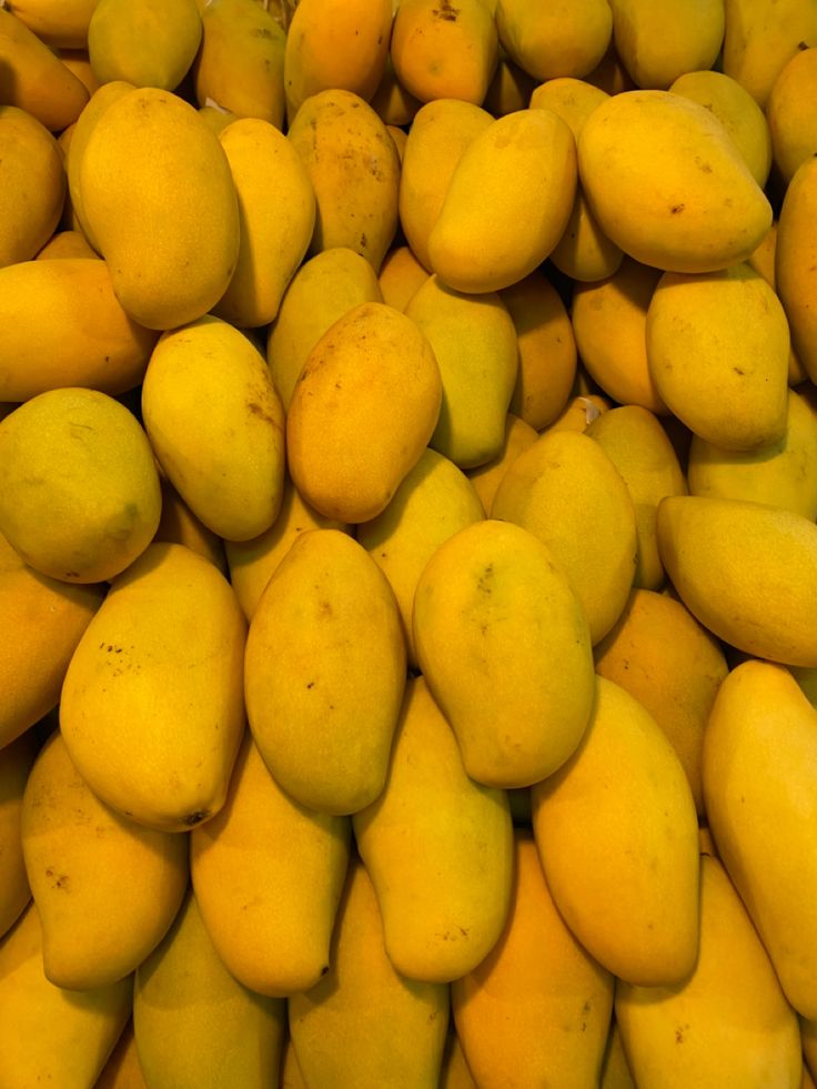 a pile of yellow mangoes piled on top of each other