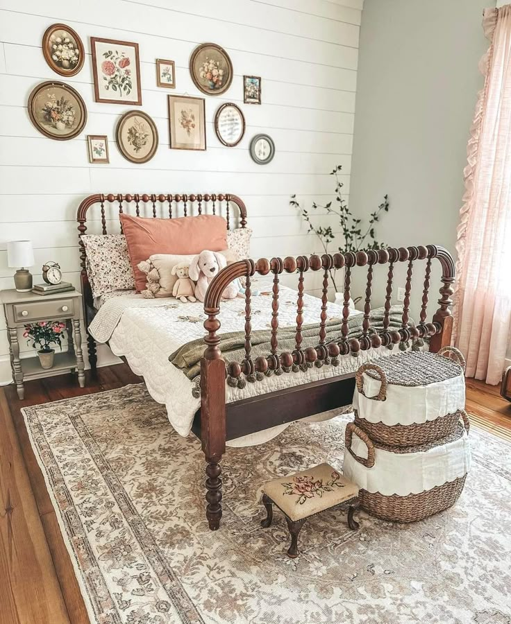 a bed sitting on top of a wooden floor next to a white wall with pictures above it