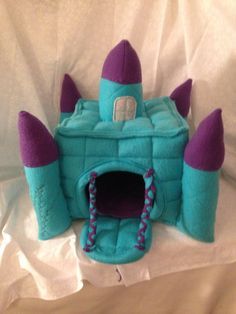 a stuffed toy castle with purple and blue spikes on it's sides sitting on a white sheet