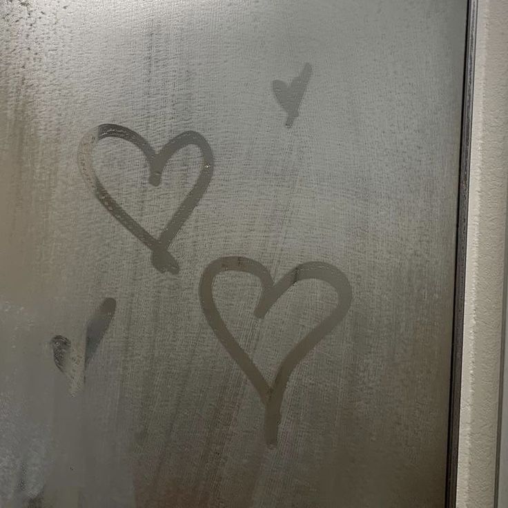 two hearts drawn on a frosted glass door with a bird in the sky behind them