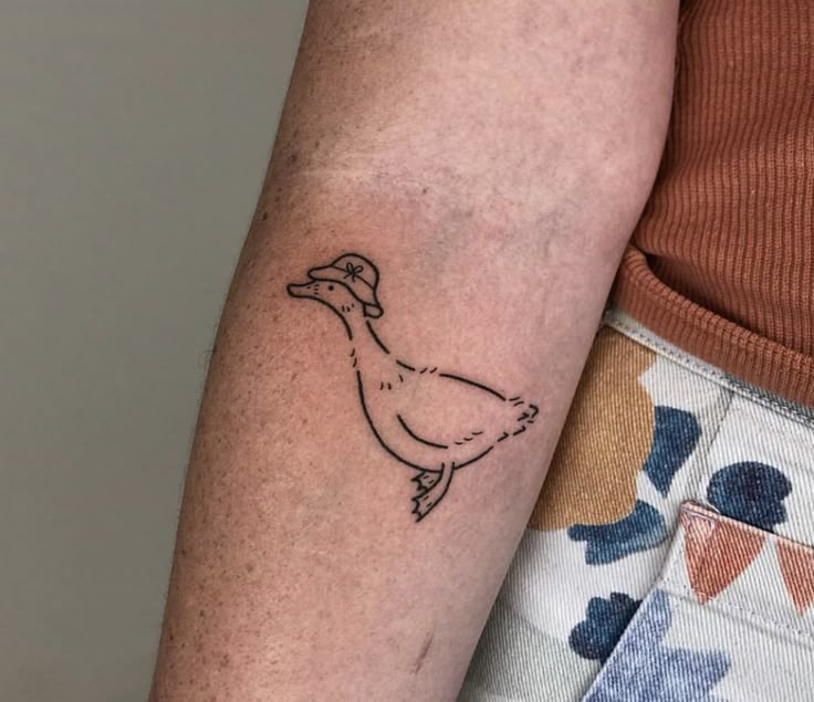 a woman's arm with a small tattoo of a chicken on the left side of her arm