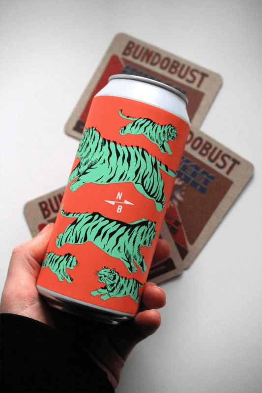 a hand holding up a can of beer with tiger designs on the front and back