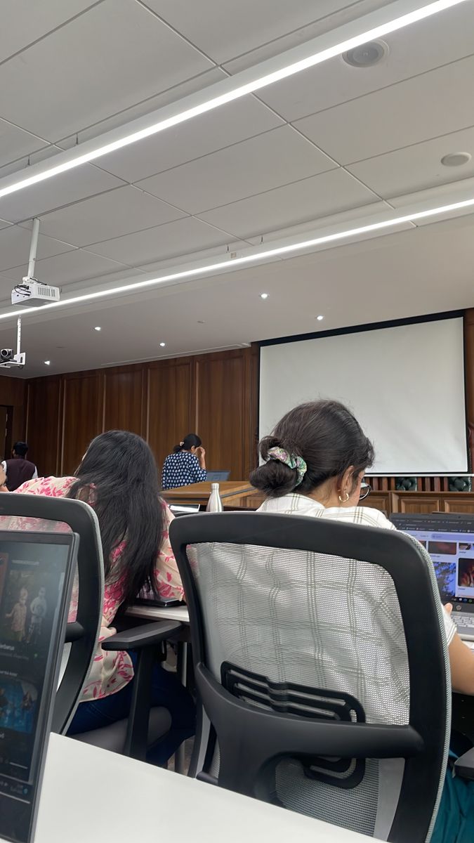 people sitting at desks in front of a projector screen