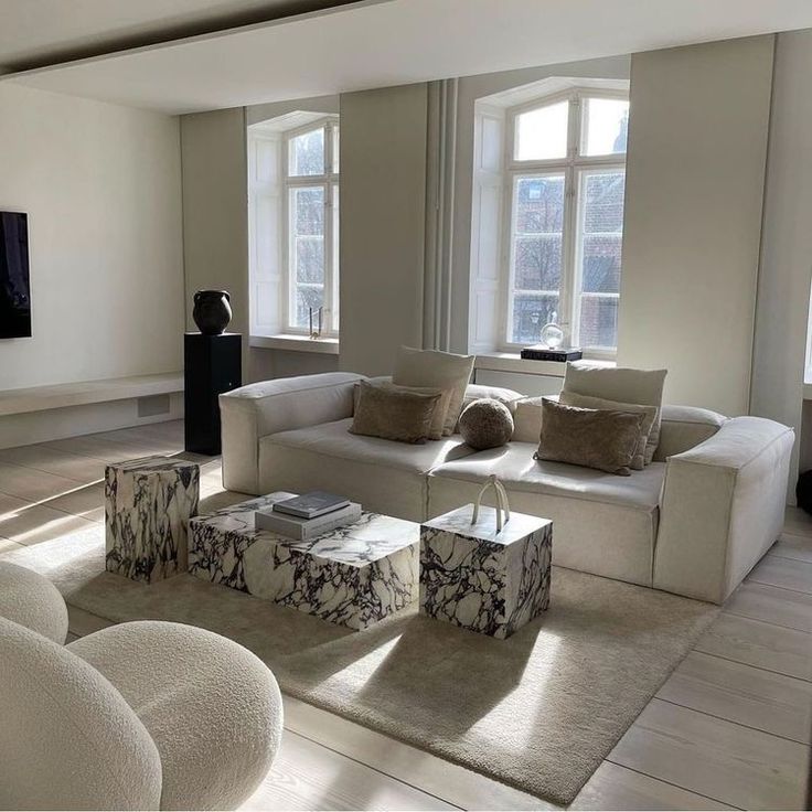 a living room filled with white furniture and large windows next to each other on top of a hard wood floor