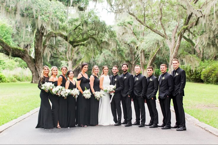 a group of people standing next to each other in front of lush green trees and bushes