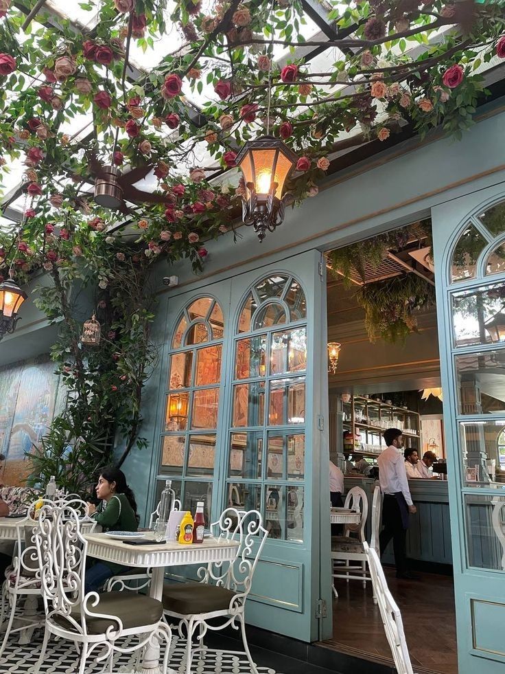 an outdoor dining area with tables, chairs and hanging flowers on the ceiling above it