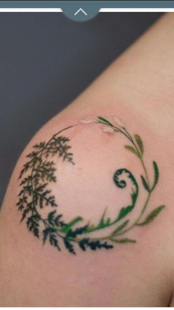 a tattoo on the arm of a woman with green leaves