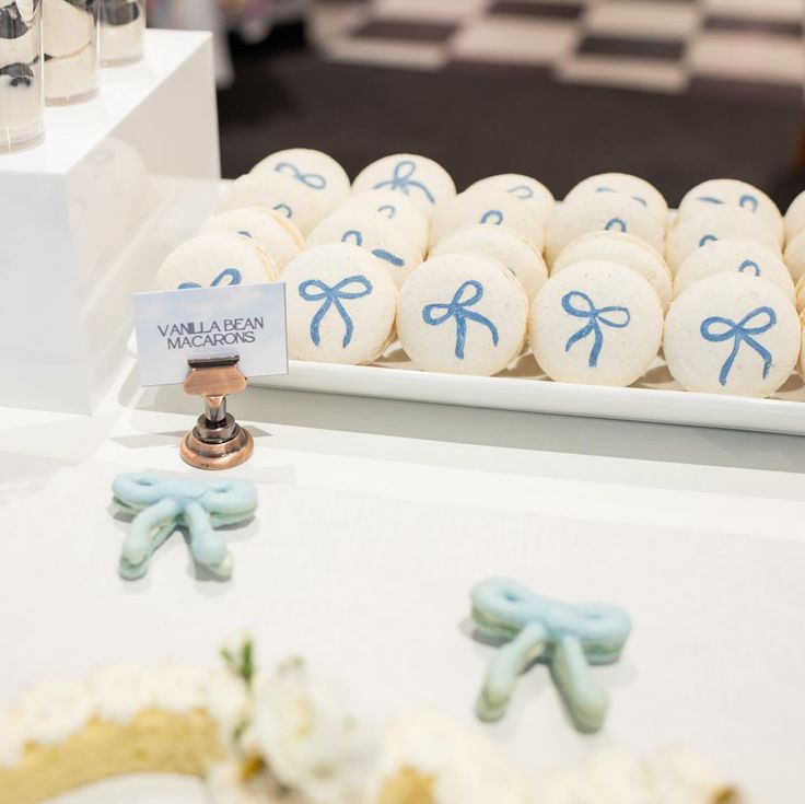 some white and blue decorated cookies on a table with other items in the back ground