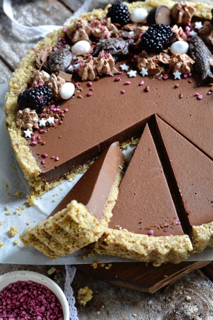 there is a chocolate cake with many pieces cut out and ready to be served on the table