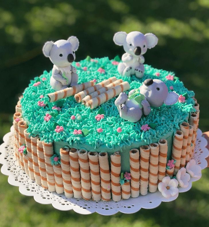 there is a cake with green frosting and two koalas on top of it