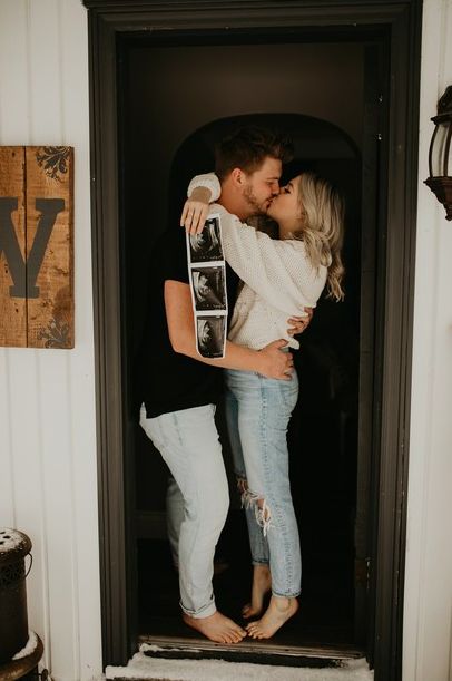 a man and woman kissing while holding a skateboard in front of a door with the letter v on it