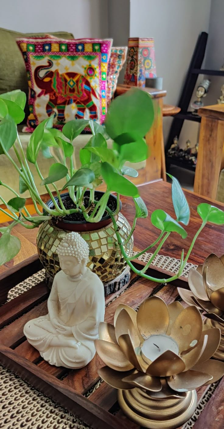 a wooden tray topped with lots of brassware and a buddha statue sitting on top of it