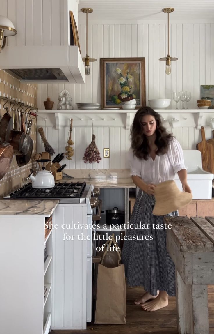 a woman standing in a kitchen next to a counter with pots and pans on it