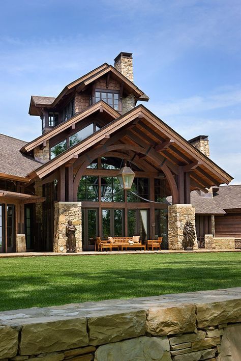 a large house sitting on top of a lush green field next to a stone wall