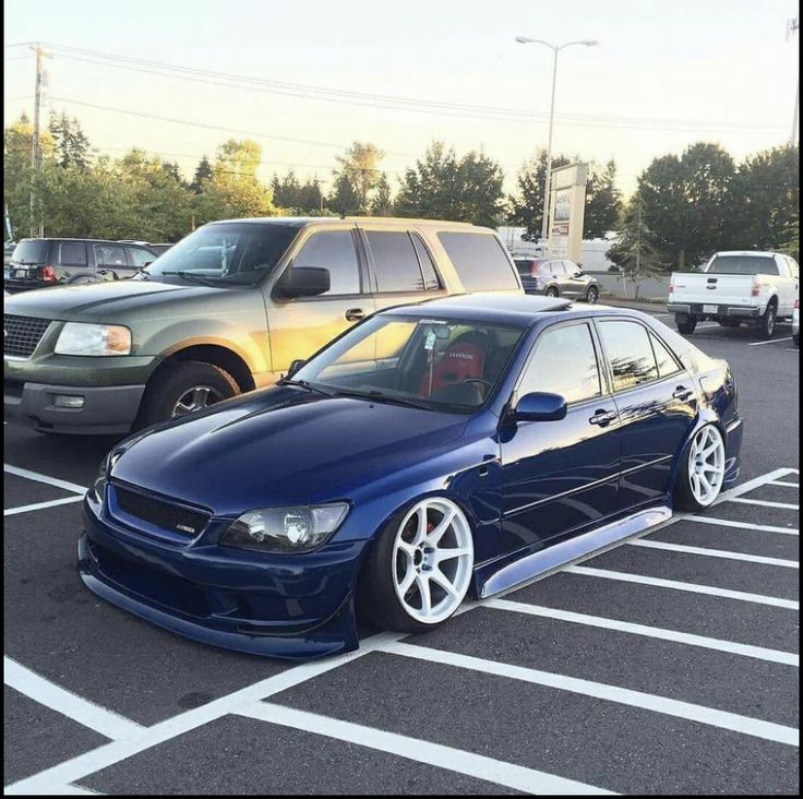 a blue car parked in a parking lot next to other cars