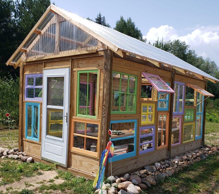 a small house made out of windows and wooden sidings on the side of a field