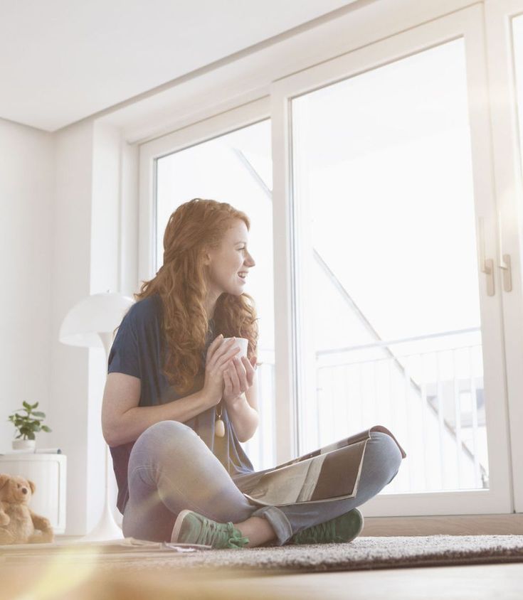 a woman sitting on the floor in front of a window