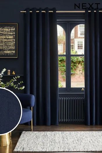 a living room with dark blue curtains and gold accents on the walls, along with a white rug