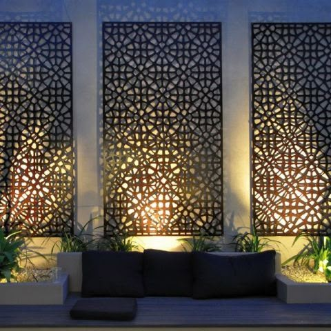 an outdoor seating area with decorative screens on the wall and potted plants next to it