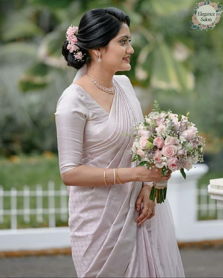 a woman in a white sari holding a bouquet of flowers