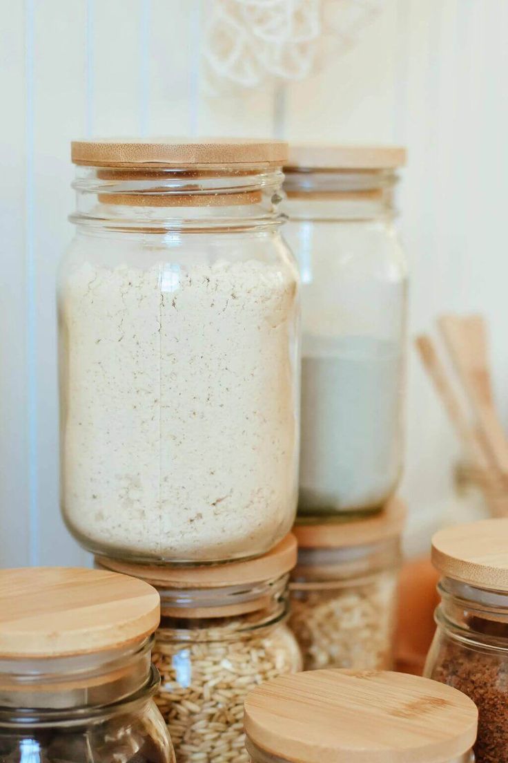 jars filled with different types of food sitting on top of a counter next to wooden spoons