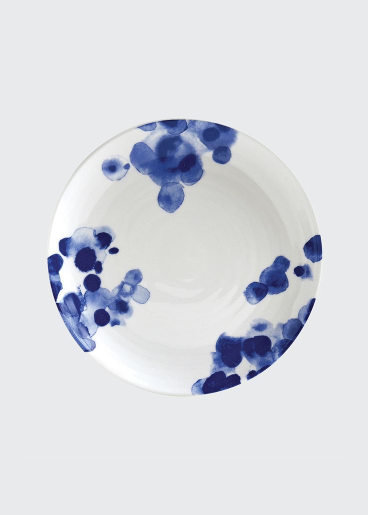 a blue and white plate with small flowers on the rim, sitting in front of a gray background