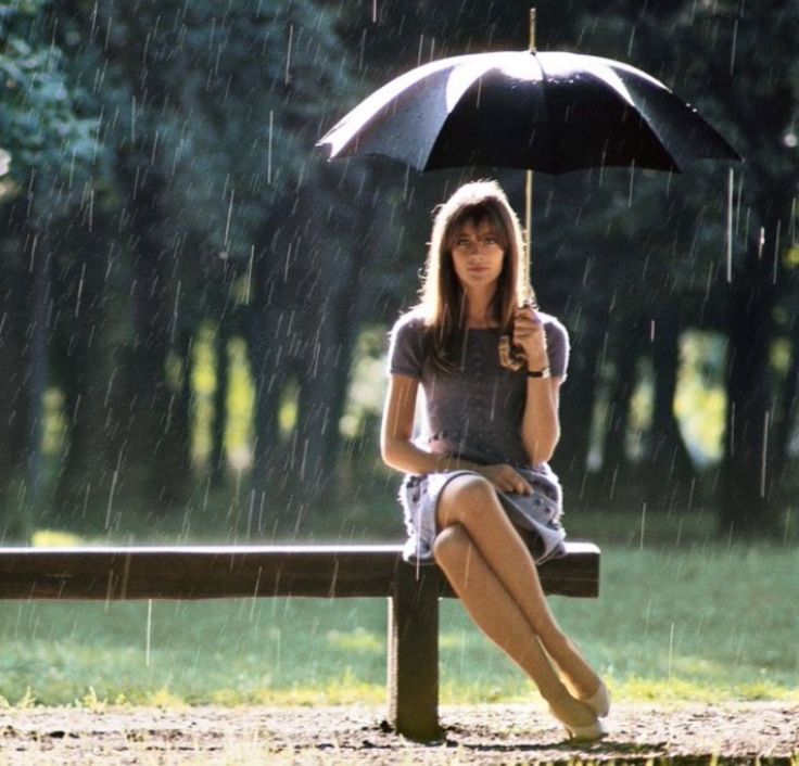 a woman sitting on a bench holding an umbrella in the rain with a quote above her