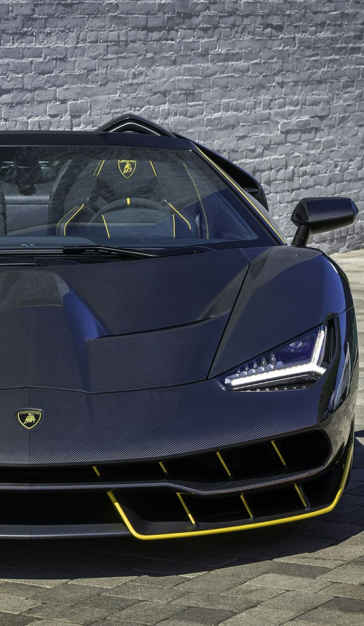 a black sports car parked in front of a white brick wall with yellow trims