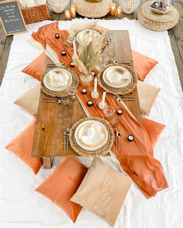 the table is set with orange and white plates, silverware, napkins, and straw hats