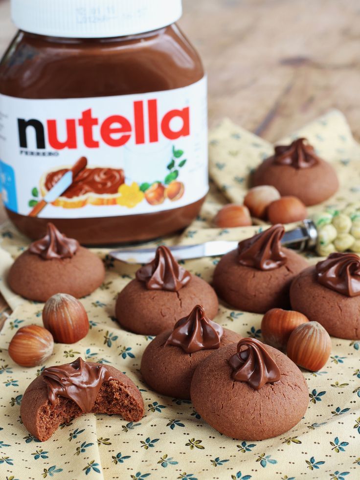 nutella cookies with chocolate frosting and nuts on a table next to a jar of nutella