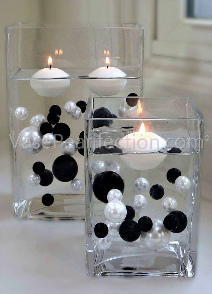 two clear vases with black and white balls in them, one filled with candles