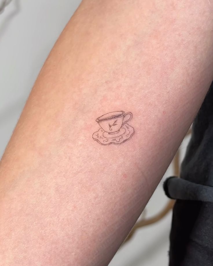 a small tattoo on the arm of a person with a cup and saucer in it