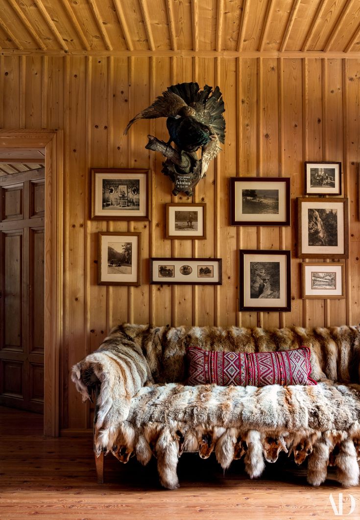 a living room with wood paneling and pictures on the wall, including an animal head