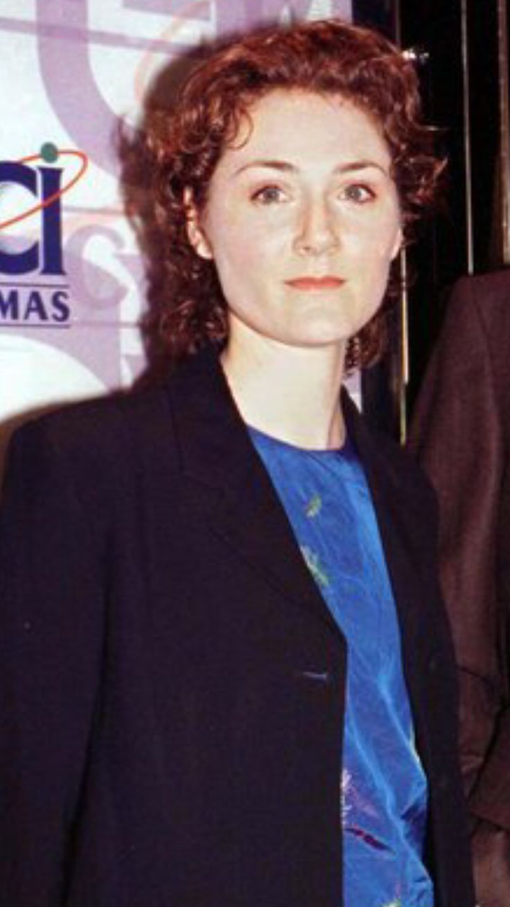 a woman standing next to a man in a black suit and blue shirt at an event