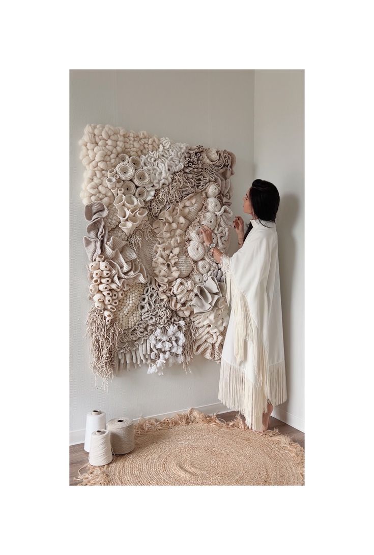 a woman standing in front of a wall hanging on the side of a white wall