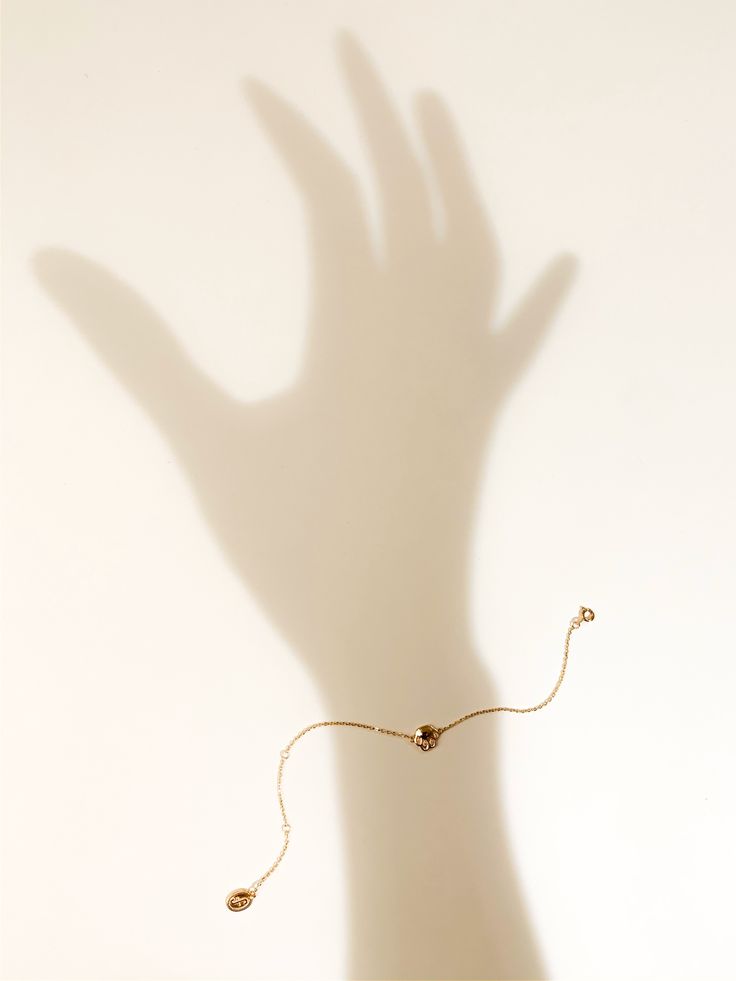 a hand casting a shadow on a wall with a beaded bracelet attached to it